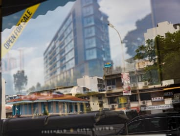 A street in Geylang is reflected in the window of a showflat for a new residential development that will be built in the area. 